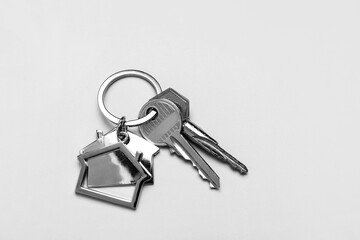 Keys with house shape keychains on grey background