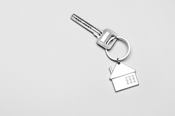 Key with house shape keychain on grey background