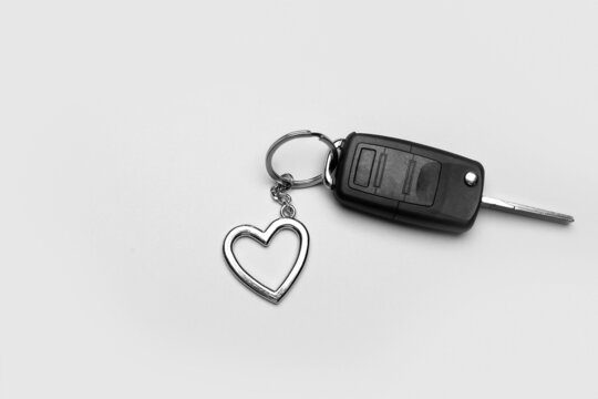 Car key with heart shape keychain on grey background