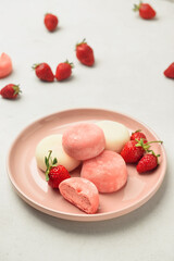 Plate with tasty Japanese mochi and strawberry on light background