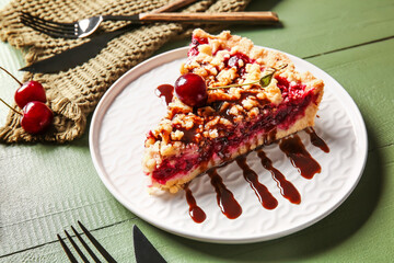 Plate with piece of tasty cherry pie on color wooden background, closeup