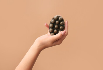 Female hand with massage soap bar on color background