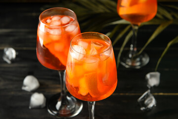 Glasses of tasty aperol spritz cocktail on dark wooden background