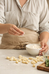 Obraz na płótnie Canvas Woman preparing tasty gnocchi at table in kitchen, closeup