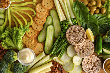 Different green vegetables, rice crackers and bowls with sauce as background