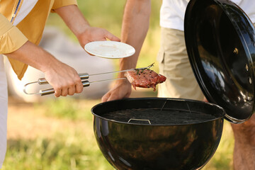 Man and his father cooking food at barbecue party on summer day