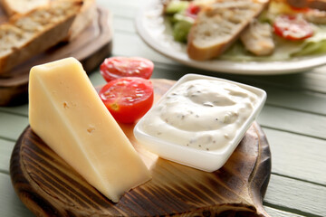 Bowl of tasty Caesar salad and parmesan cheese on table