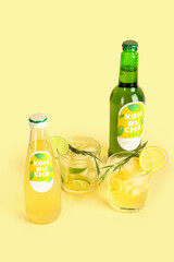 Bottles and glasses of fresh kombucha tea on color background