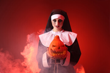 Woman dressed for Halloween as nun with pumpkin on color background