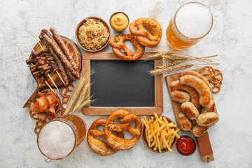 Mugs of cold beer, wooden board with Bavarian sausages, blank chalkboard and snacks on light background. Oktoberfest celebration