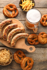 Mug of cold beer, board with Bavarian sausages and snacks on wooden background. Oktoberfest celebration