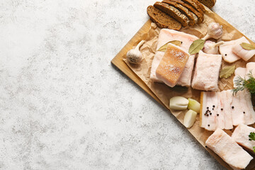Wooden board with salted lard and bread on light background
