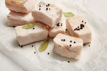 Parchment with pieces of salted lard on light background