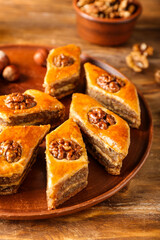 Plate with tasty baklava on wooden background, closeup