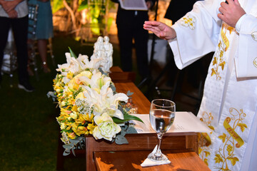 priest blessing water in religious ceremony, ornamental flowers