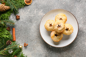 Plate with tasty mince pies and Christmas decor on grunge background