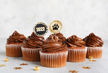 Tasty cupcakes for New Year 2022 celebration on grunge background
