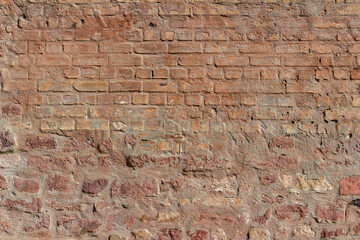 Reddish brown color European  medieval stone and brick wall texture background in bright sunlight, with copy space
