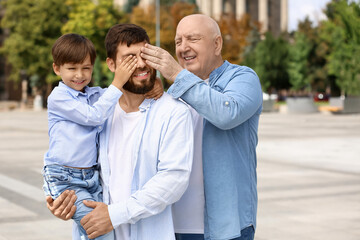 Obraz premium Happy man, his little son and father walking outdoors