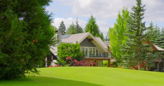 Establishing shot of two story stucco luxury house with golf course foreground, big tree and nice landscape in Vancouver, Canada, North America. Day time on June 2021. ProRes 422 HQ.