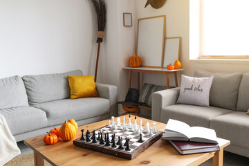 Table with chess, pumpkins and books in living room