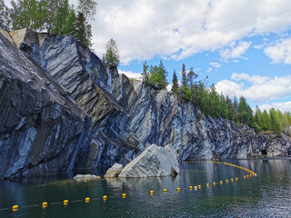 A view from below of the rocky shore and a huge rock that fell into the emerald water of the Marble...