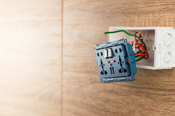 Universal wall outlet AC power plug with USB port with on-off in a plastic box on a wooden wall.