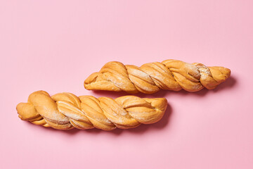 Two fresh braided breads isolated on pink background with copy space. Horizontal photo.