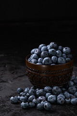 Fresh juicy blueberries in the bowl on the black background. Low key photography