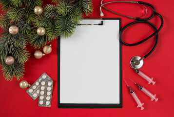 Celebrating Christmas in health care. Flat lay top view. Stethoscope, fir branches with ornaments on a white background. Top view, flat lay.