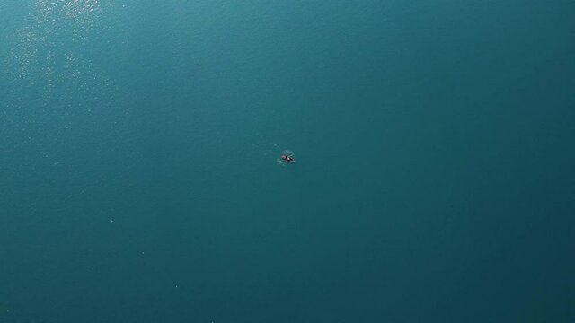 AERIAL Top Down View of a Single Boat Rowing in a Still Blue Lake
