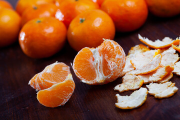 Closeup of peeled and whole clementines on dark wooden background © JackF
