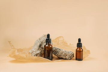 Mock-up of a set of empty cosmetic containers with pipettes made of amber glass on a beige...