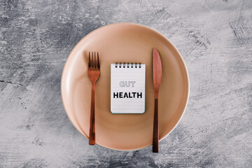 gut health text on notepads on top of dining plate with fork and knife, healthy nutrition and...