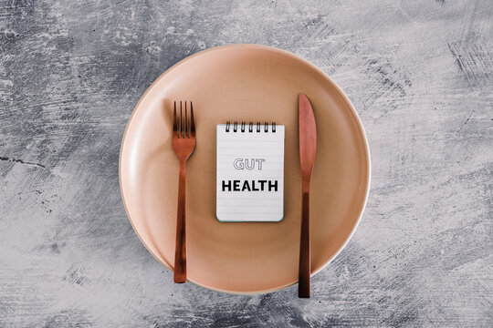 gut health text on notepads on top of dining plate with fork and knife, healthy nutrition and scientific research