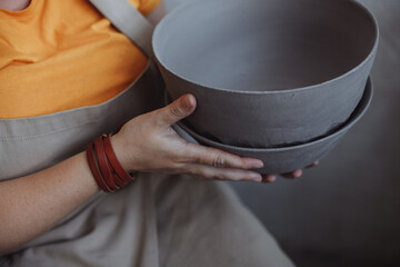 Middle-aged plus-sized woman in a pottery workshop with her eco-friendly clay utensils