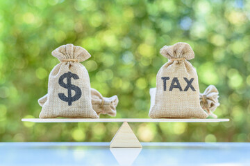 Income tax collection, strategy for paying tax, financial concept : Tax, dollar money bags on a simple / basic balance scale, depicts planning for reducing tax liability e.g investment and retirement