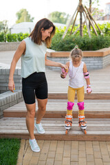 Caucasian woman teaches her daughter to skate on roller skates.