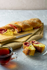 a knife for cherry-vanilla strudel and a cup of tea on a light gray surface, two pieces of strudel lie on a saucer
