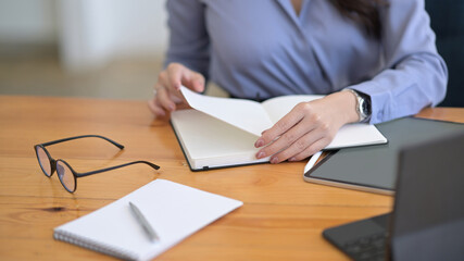 Businesswoman reading information on notebook and working with digital tablet.