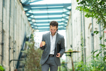 A young successful businessman is walking down the street. Man in a casual wear. Business, freelance and remote work.