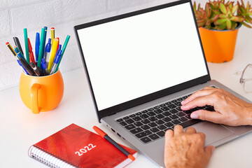 Mature woman typing on keyboard using laptop computer. White desktop and brick wall. Work, social, technology concept