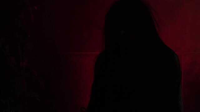 Silhouette of a witch with shimmering light with smoke and red light.