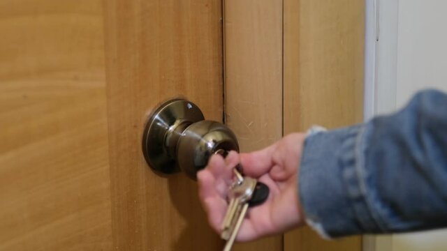 Woman using a key to open the lock of the front door. woman returns home, a girl enters the room