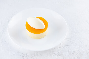 Mousse cake with mango and passionfruit on a white plate.