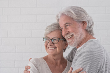 Beautiful couple of two happy senior people hugging each other - standing smiling at home - serene retirement concept