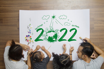 Top view happy family lying on floor, With creative painting 2022 New year earth eco environmental...