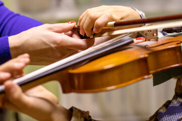 teacher's hand straightens the right hand of the young violinist who holds the neck while playing the violins, goizontal