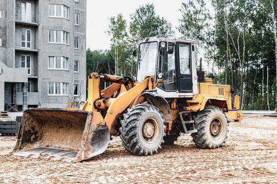 Heavy wheel loader with a bucket at a construction site. Equipment for earthworks, transportation and loading of bulk materials - earth, sand, crushed stone.