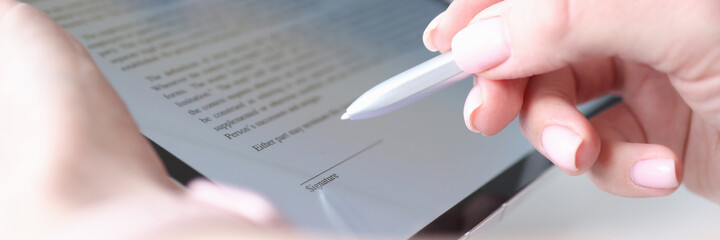 Woman hand holds stylus and puts an electronic signature in contract on tablet